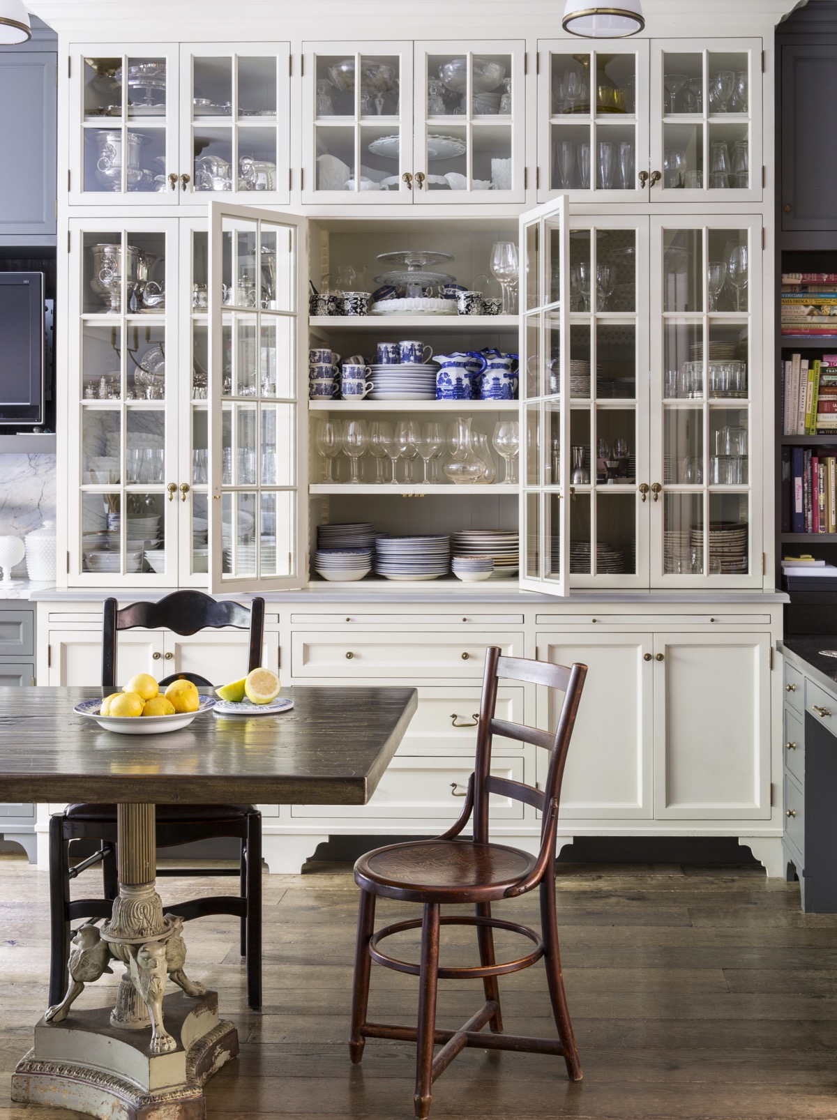 Kitchen with floor to ceiling white wood cabinets with various glasses, dishes, etc.