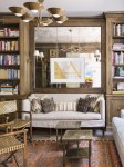 Library with built in loveseat, wall mirror and floor to ceiling shelves with various books.