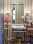 Powder bathroom with striped vertical wallpaper, ceramic basin with metal framework, matching wall sconces.